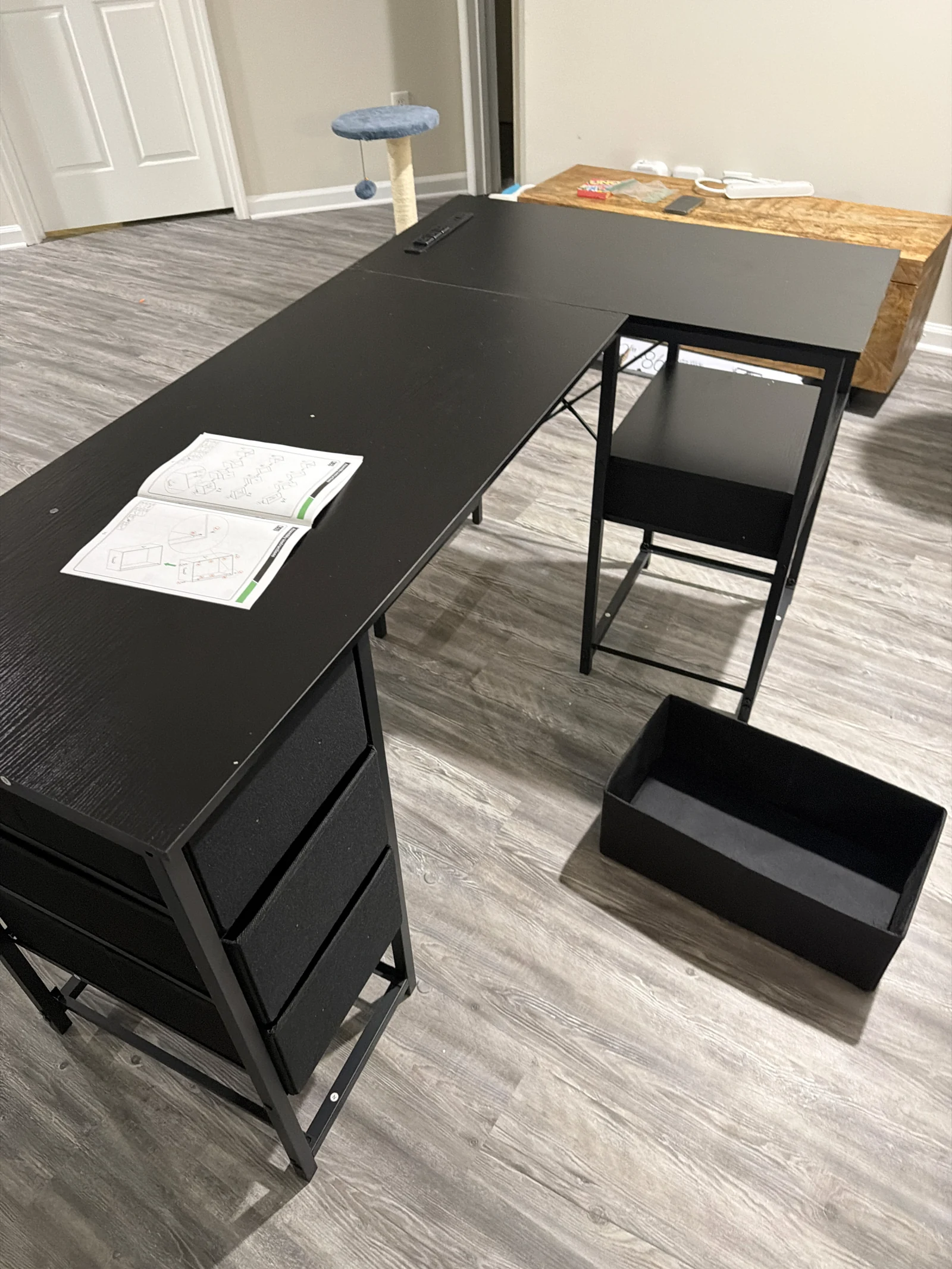 Black corner desk during assembly with a drawer beside it
