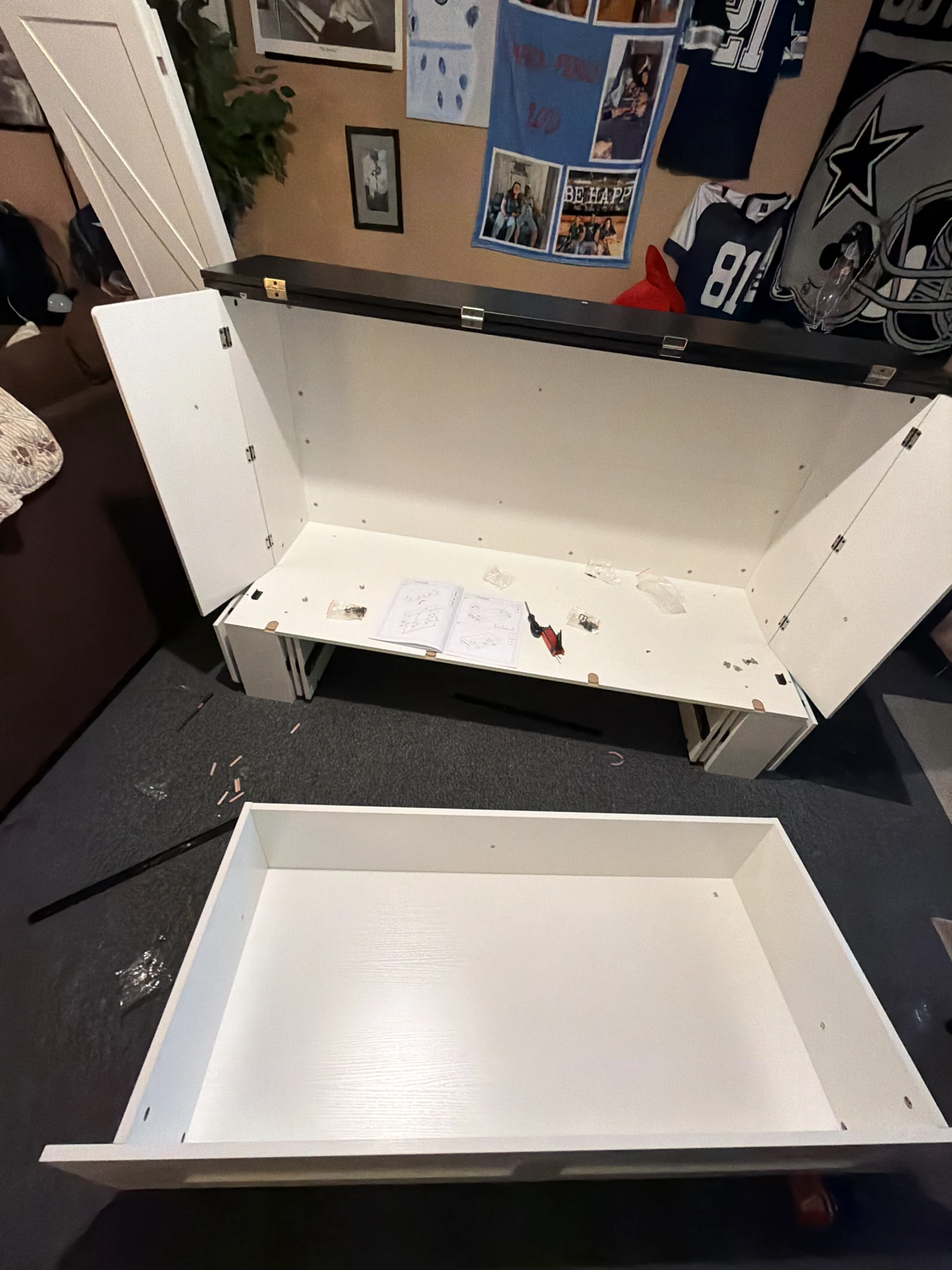 White cabinet components with doors open and a drawer during assembly