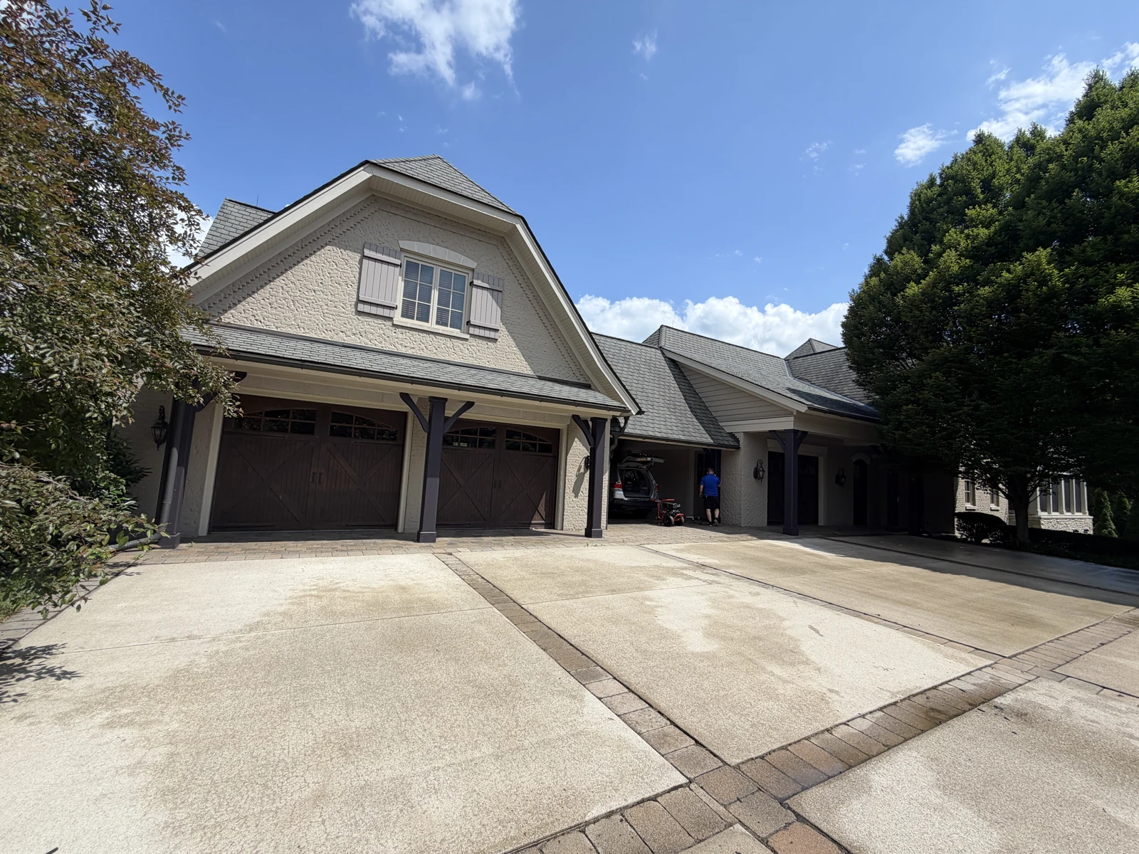 Wide driveway and garage view with pressure-washing equipment at the worksite