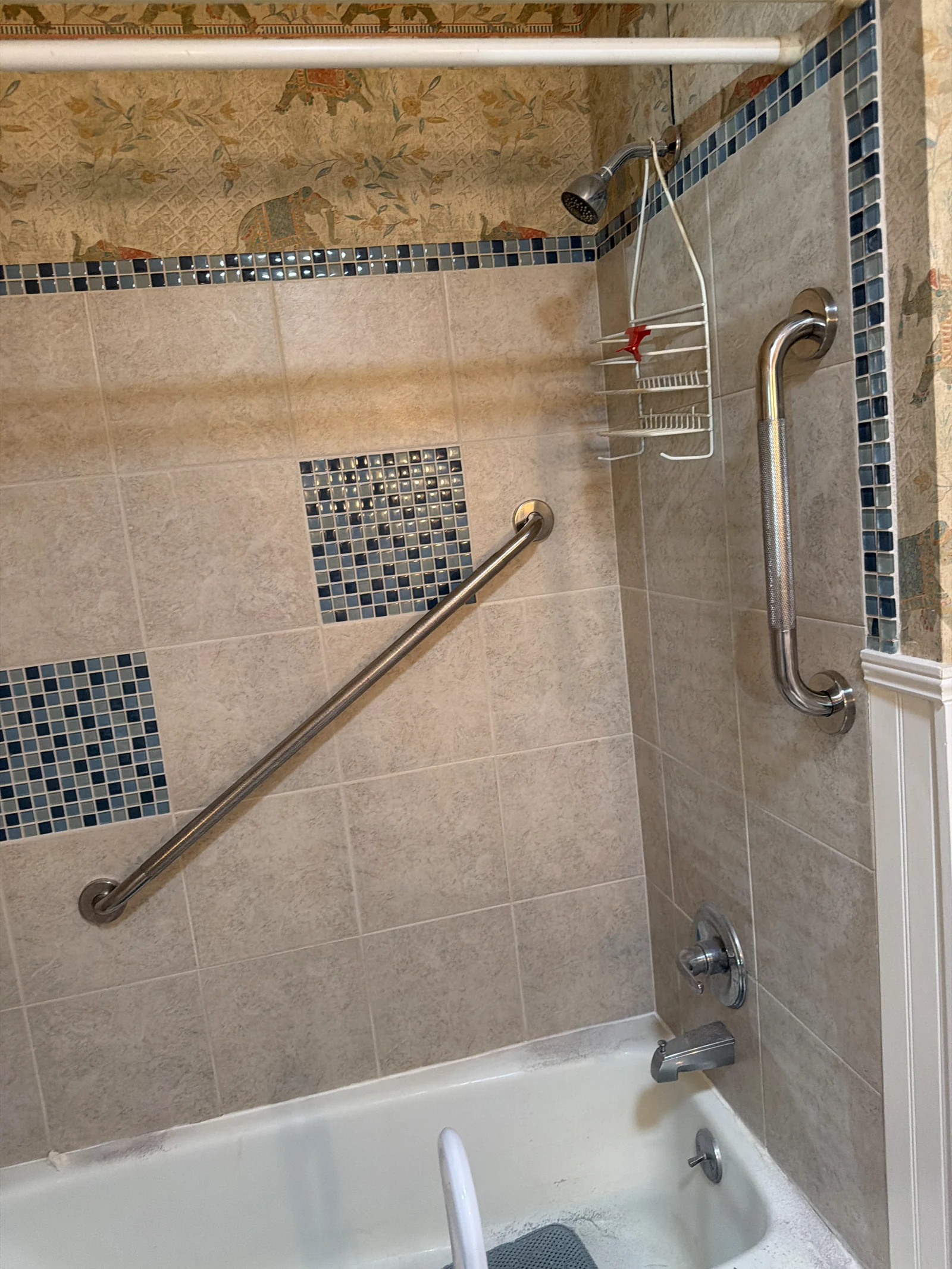 Diagonal and vertical stainless-steel grab bars installed beside a bathtub with blue mosaic tile