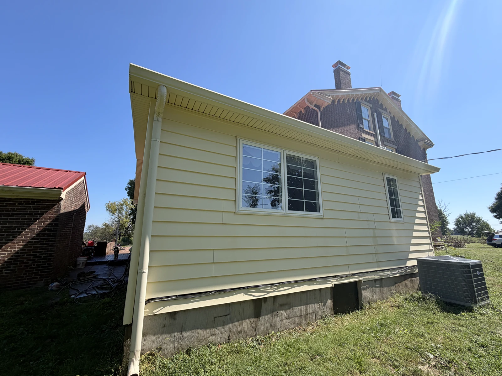 The same yellow-sided wall and windows after house washing