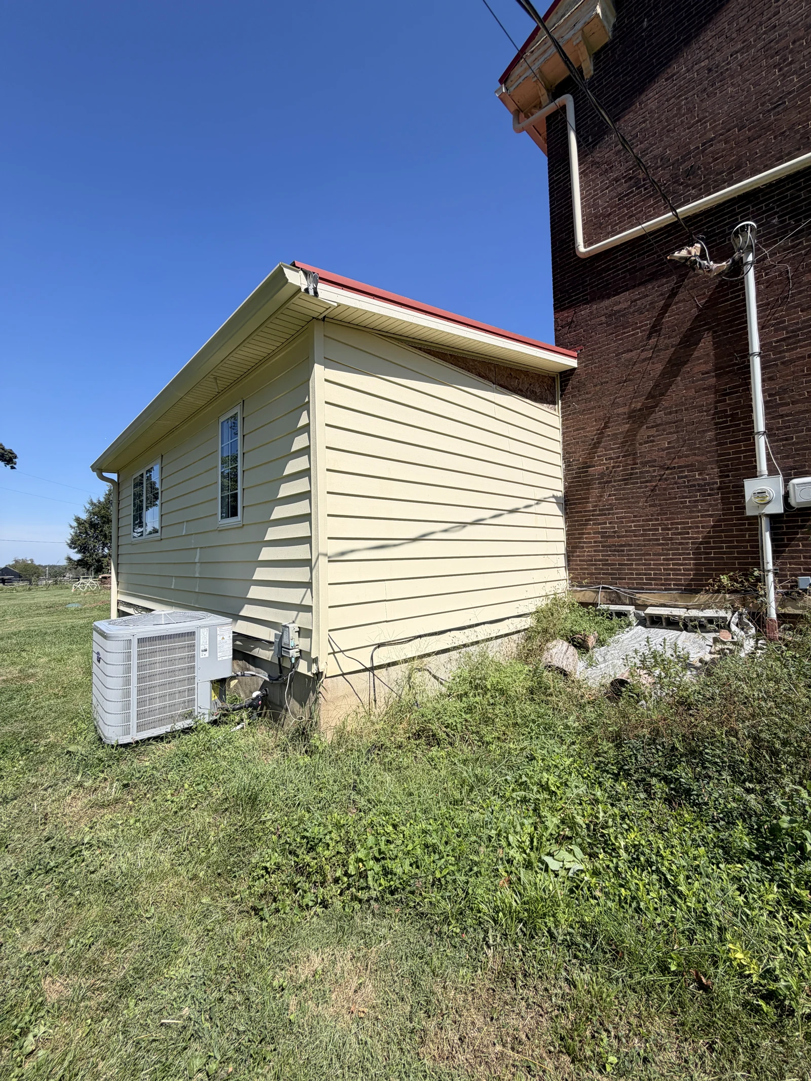 Rear corner of the yellow-sided addition following washing, with existing unfinished trim visible