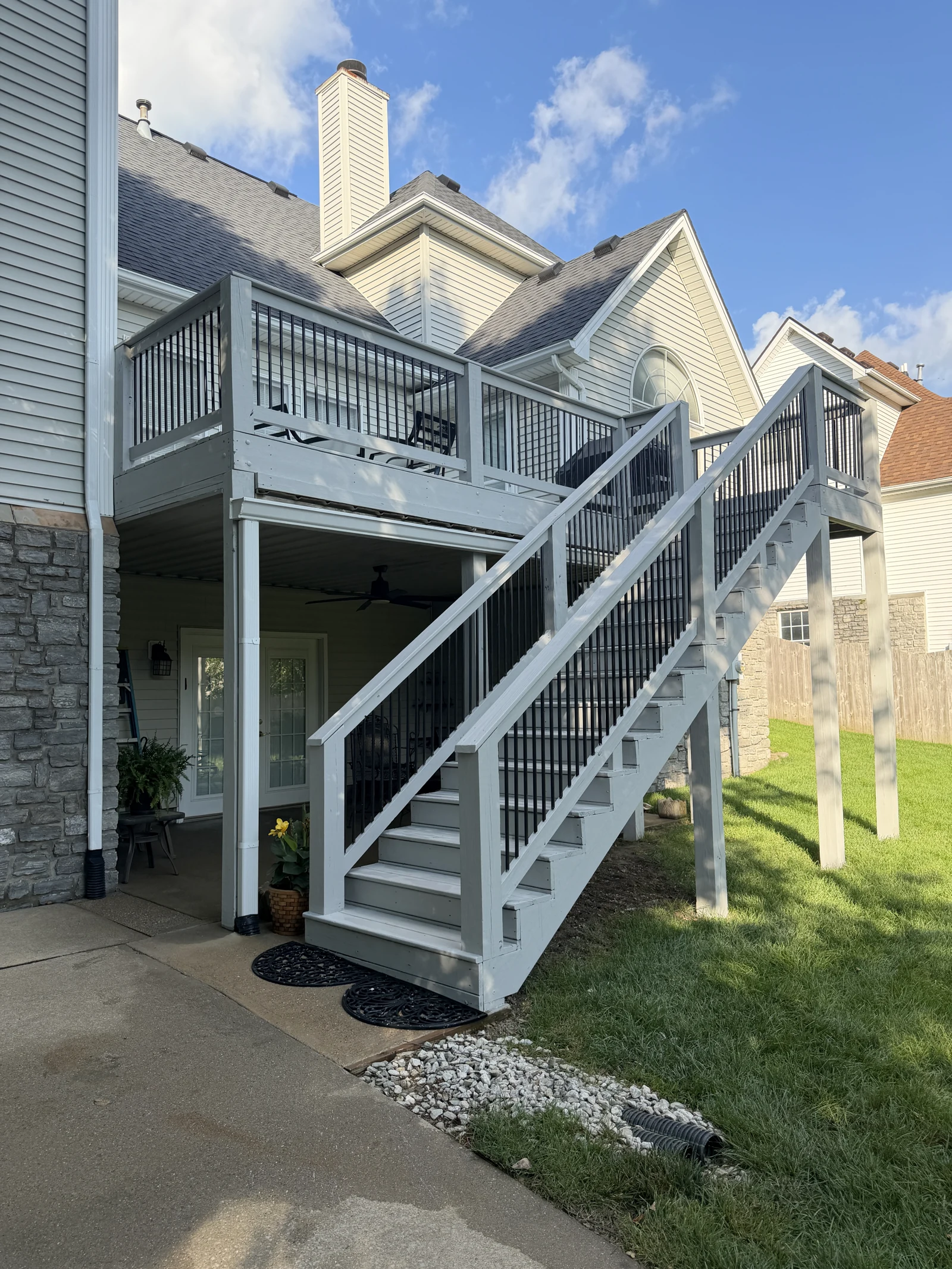 Painted raised deck, railings and staircase beside a home