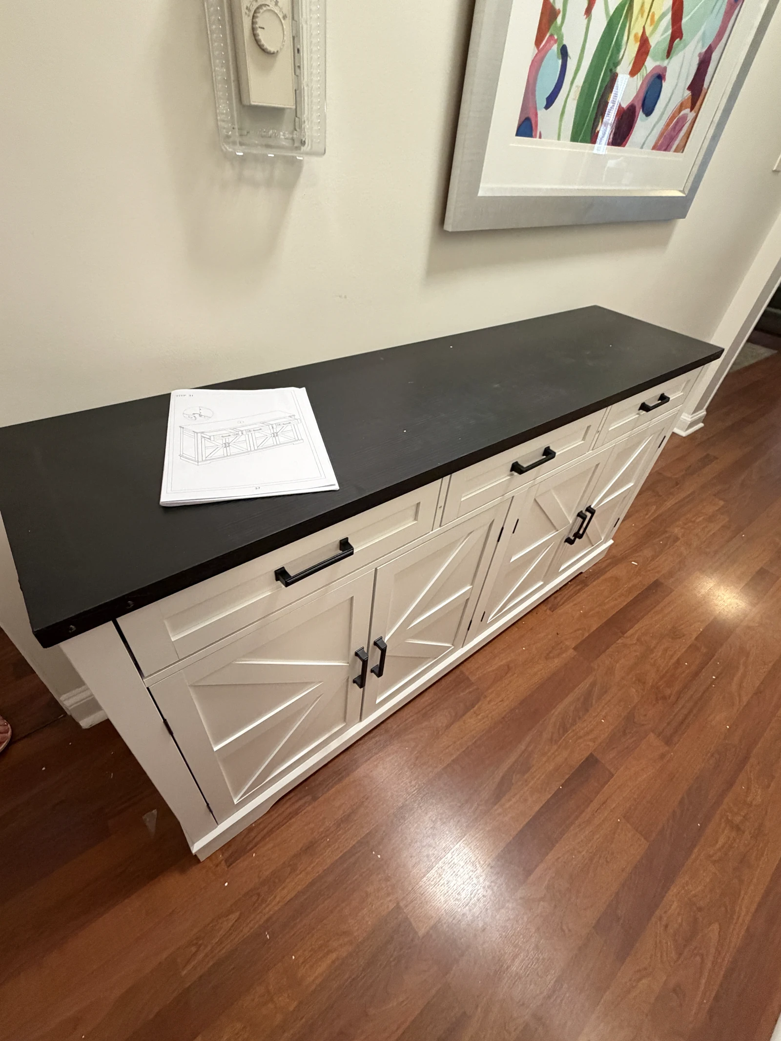 Assembled white sideboard with a dark top and wood floor beneath