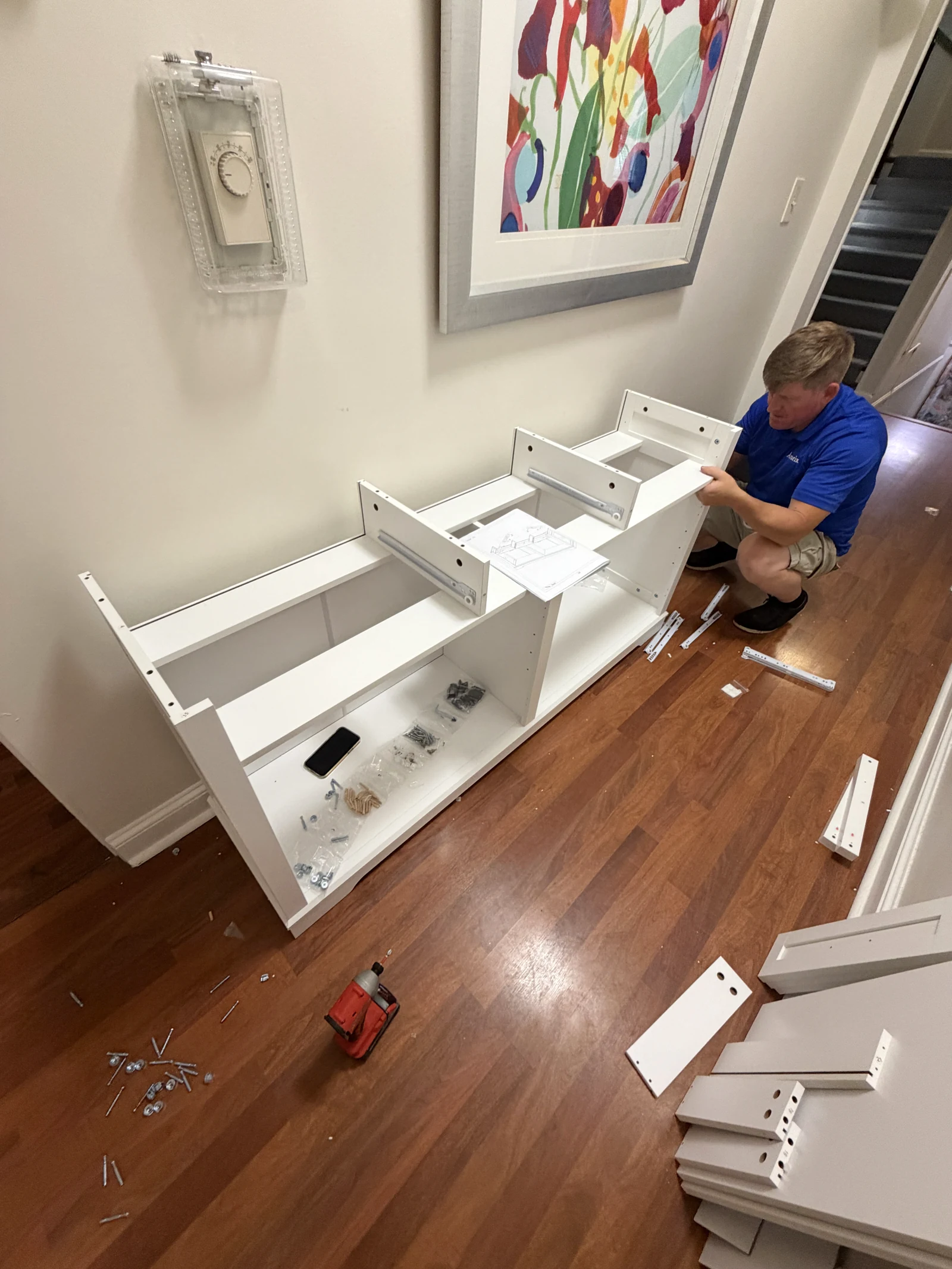 Arorix team member assembling a white sideboard in a hallway