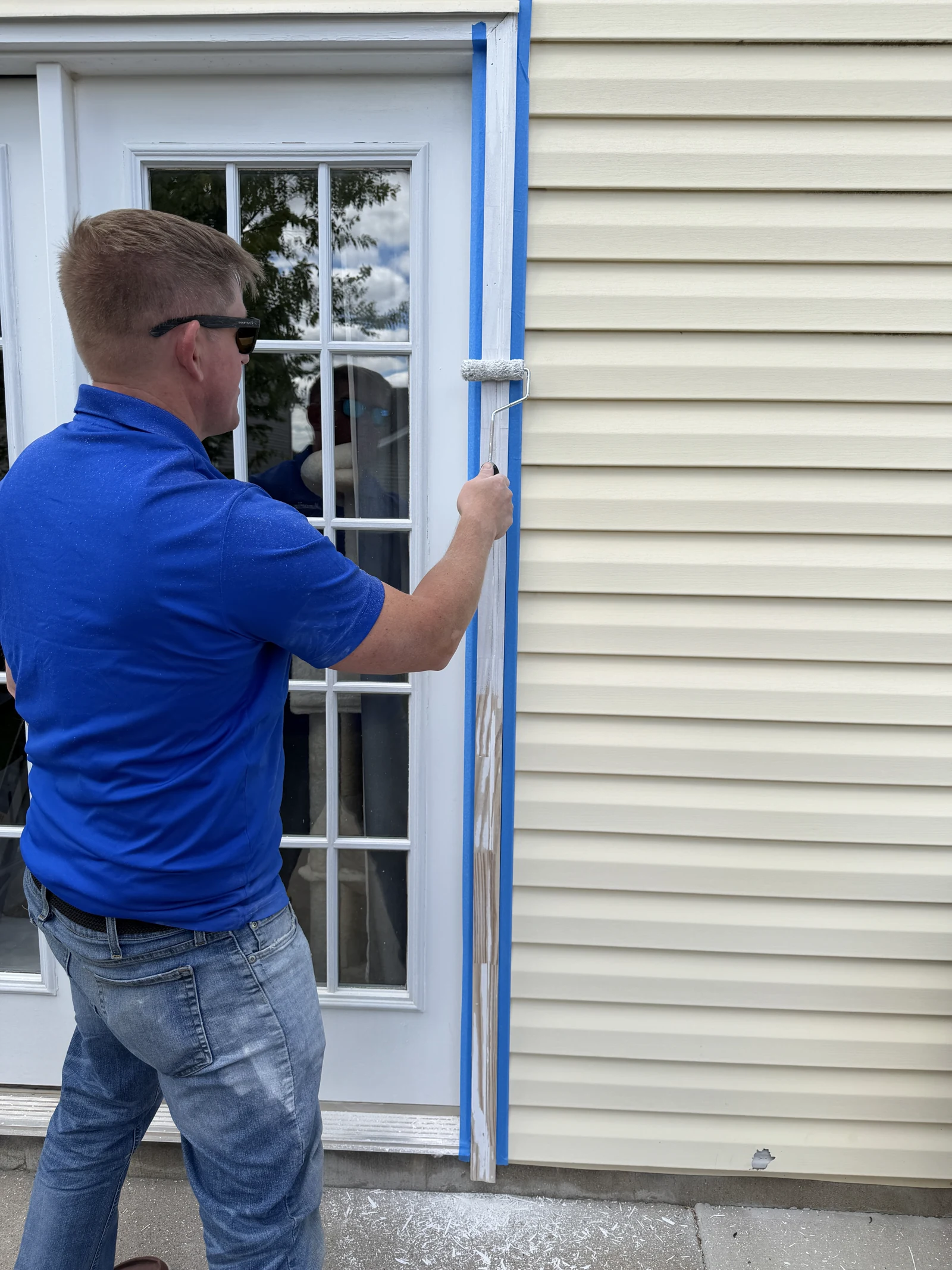 Arorix technician painting exterior door trim with protective masking in place