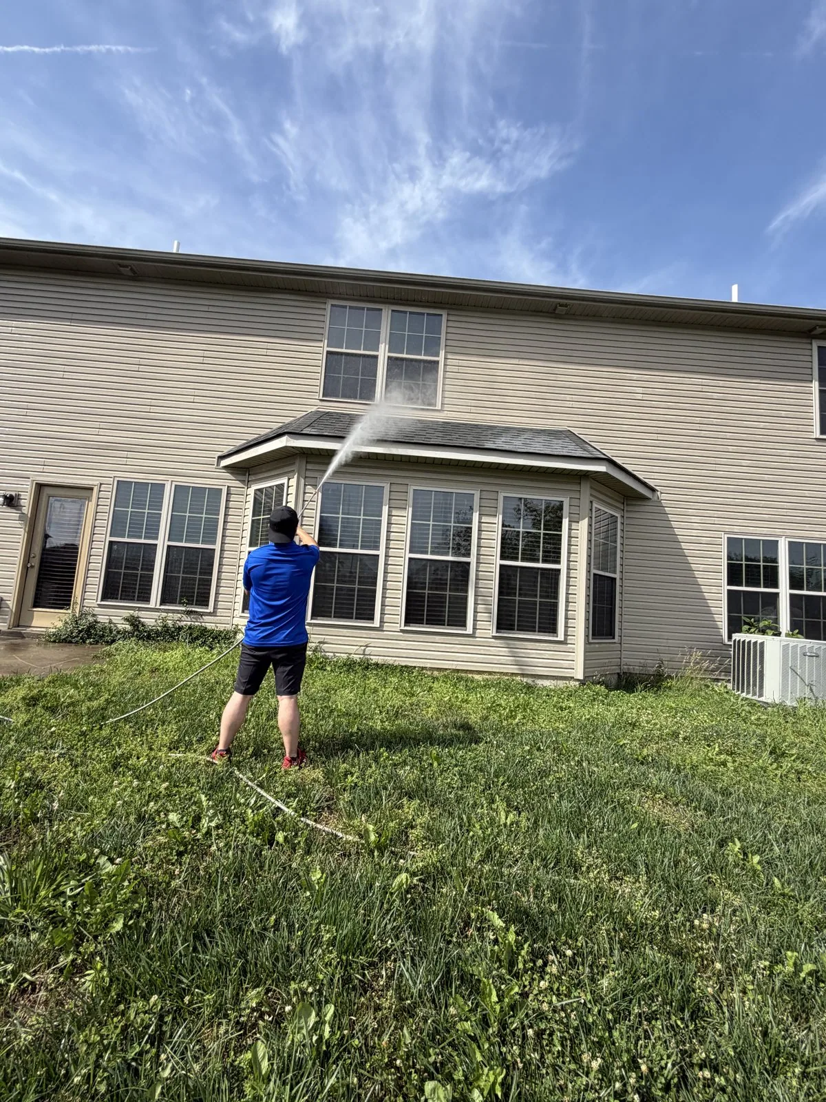 Arorix technician applying a house soft-wash treatment to siding on a Lexington Kentucky home