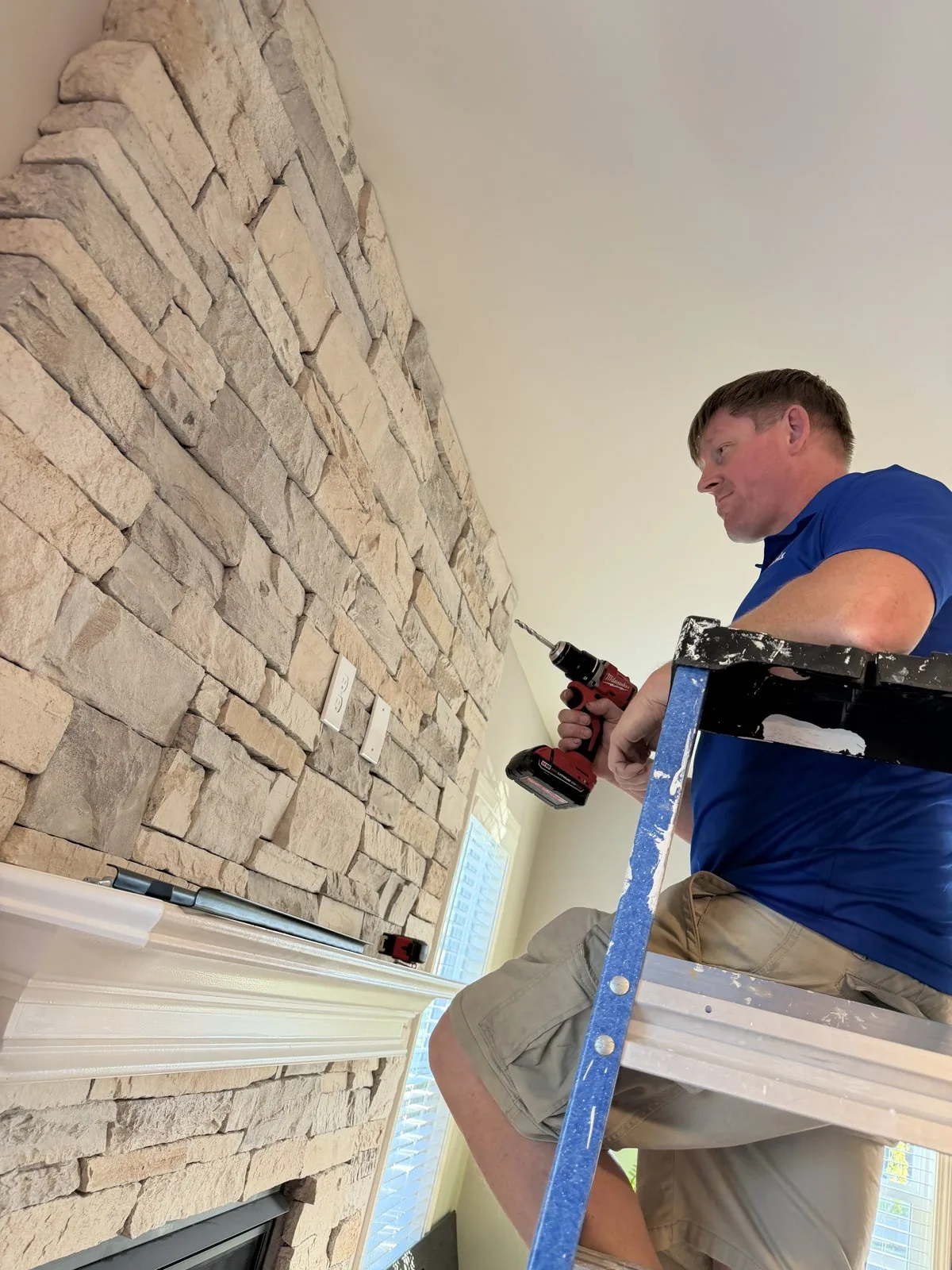 Arorix technician mounting a television above a stone fireplace in Lexington Kentucky