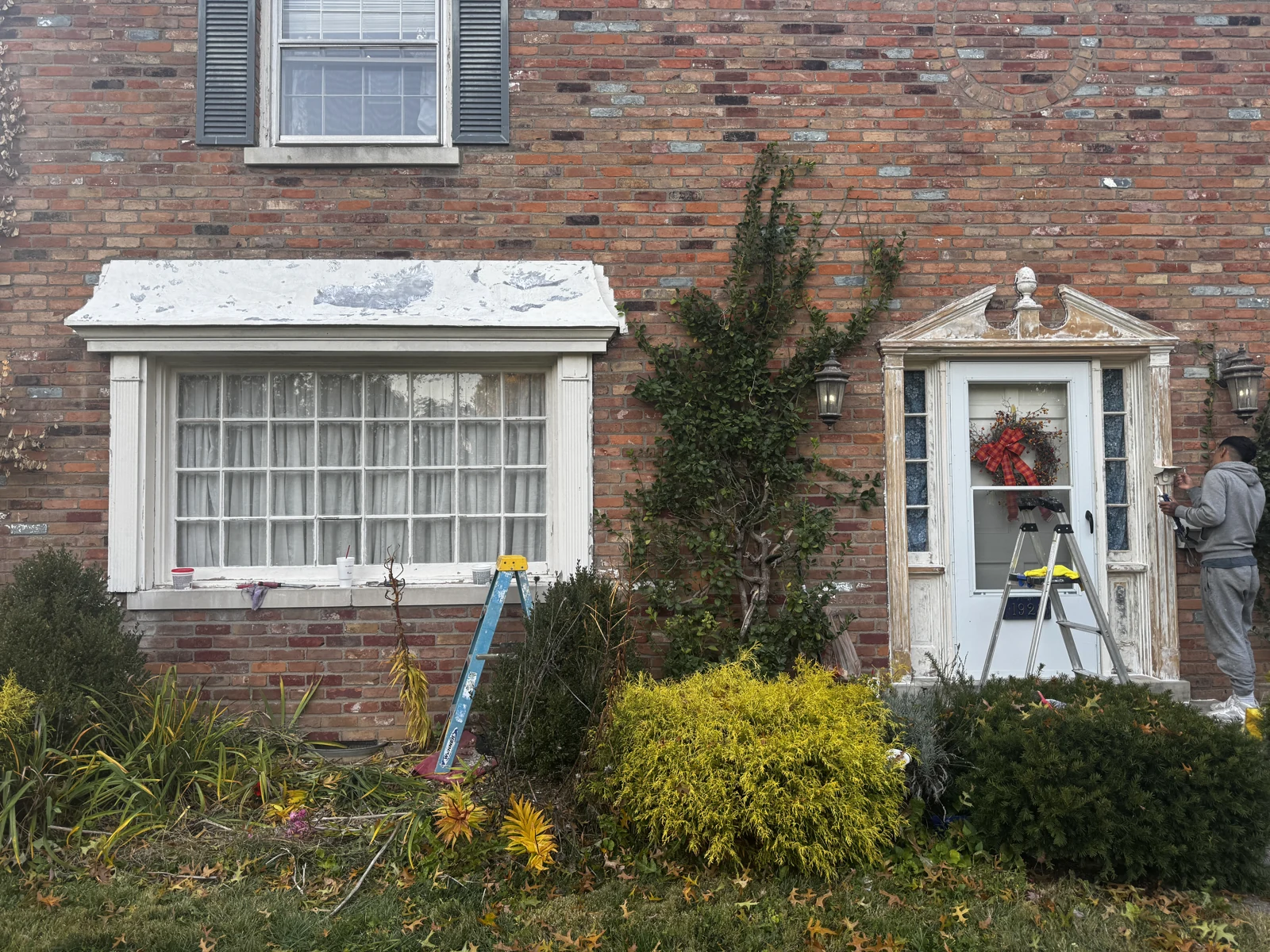 Weathered window canopy and entry trim before restoration on a brick home