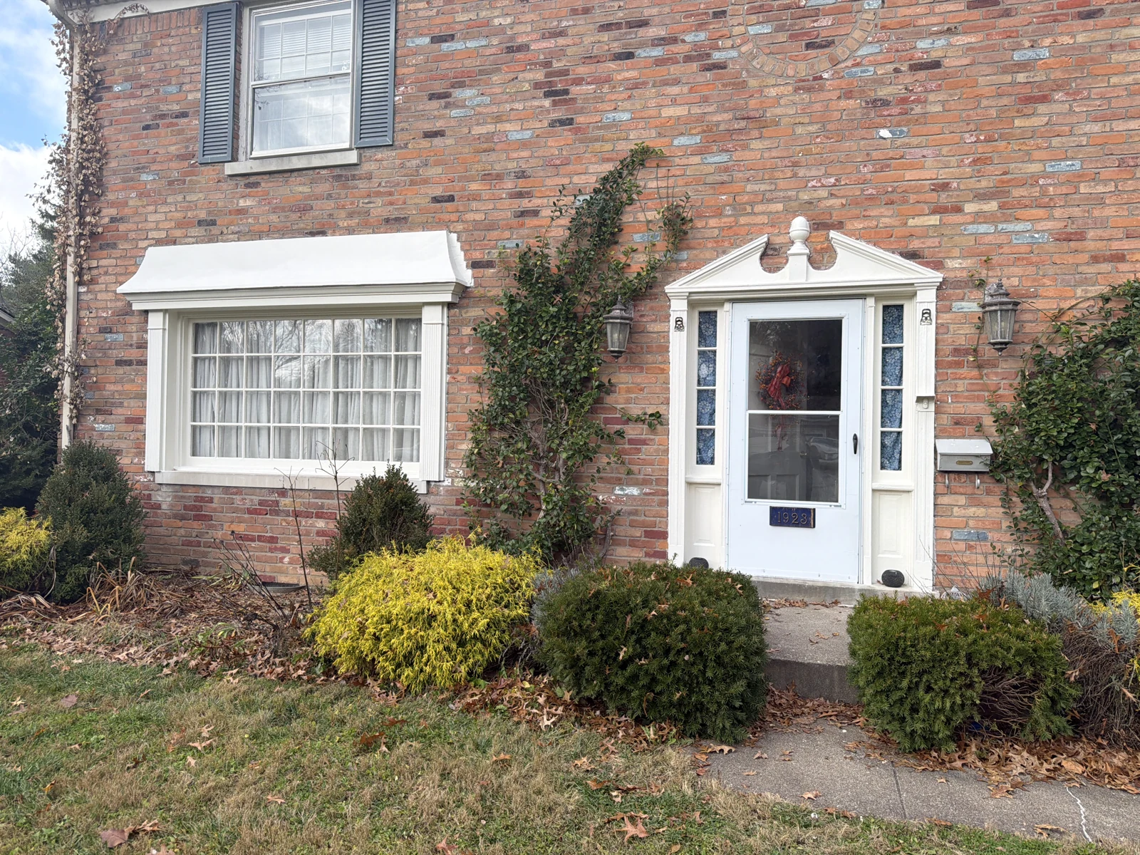 Restored white window canopy and entry trim on a brick home